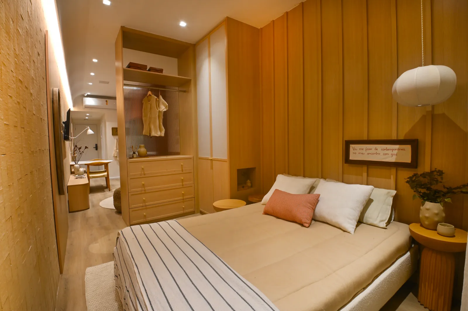 Cama com manta listrada e painel de madeira