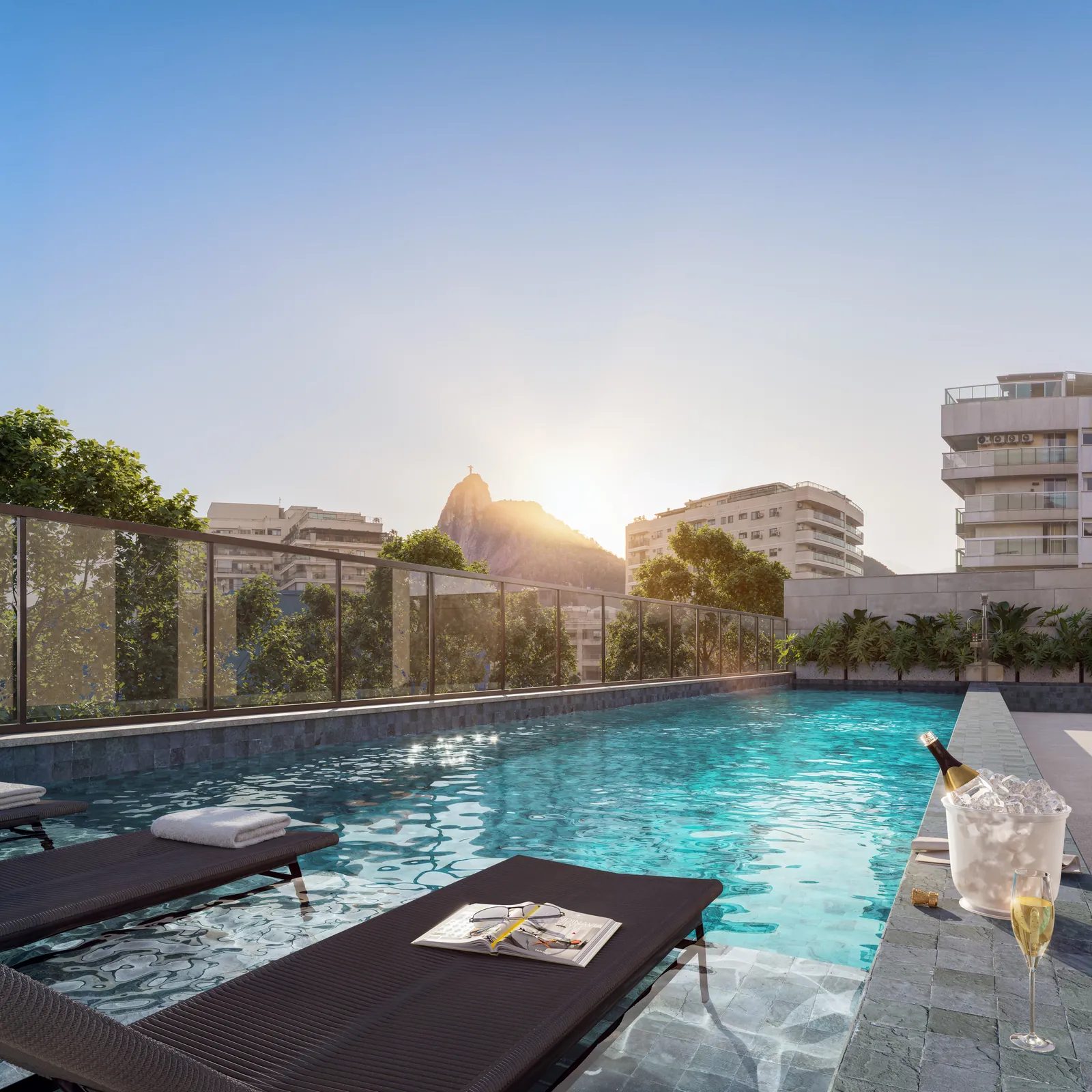 A piscina do Arq com espreguiçadeira e o Cristo ao fundo, ao pôr do sol