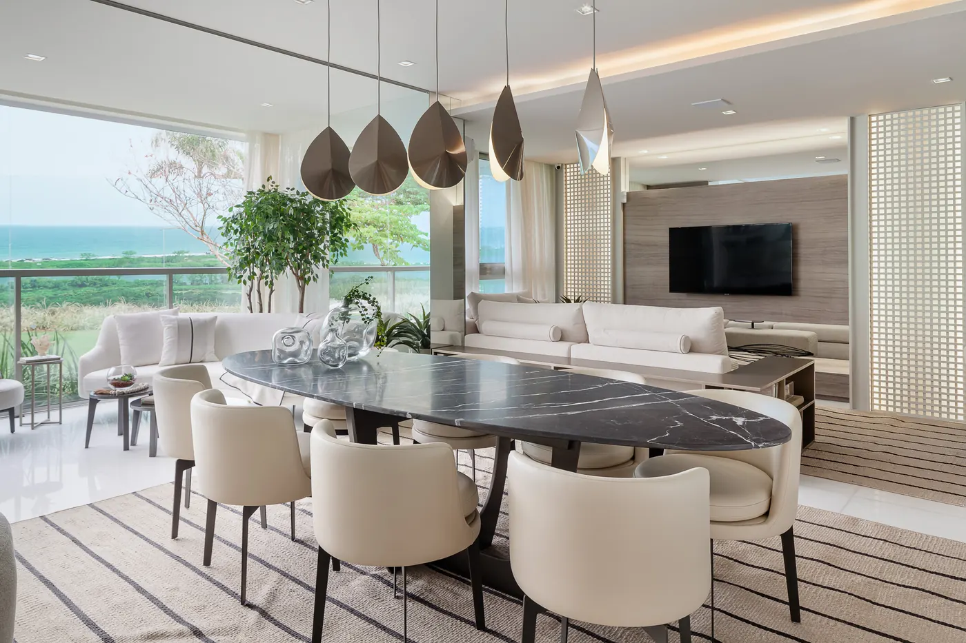 Sala de jantar do decorado de 181 m², com mesa oval e vista para a lagoa