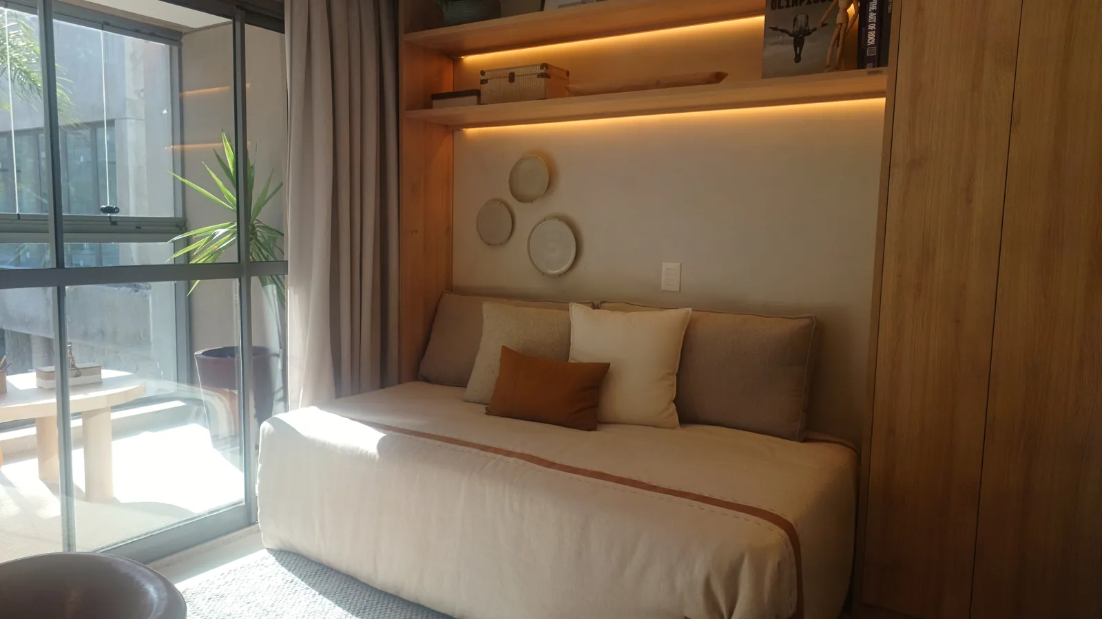 Suíte com cama, cabeceira de madeira e porta para a varanda