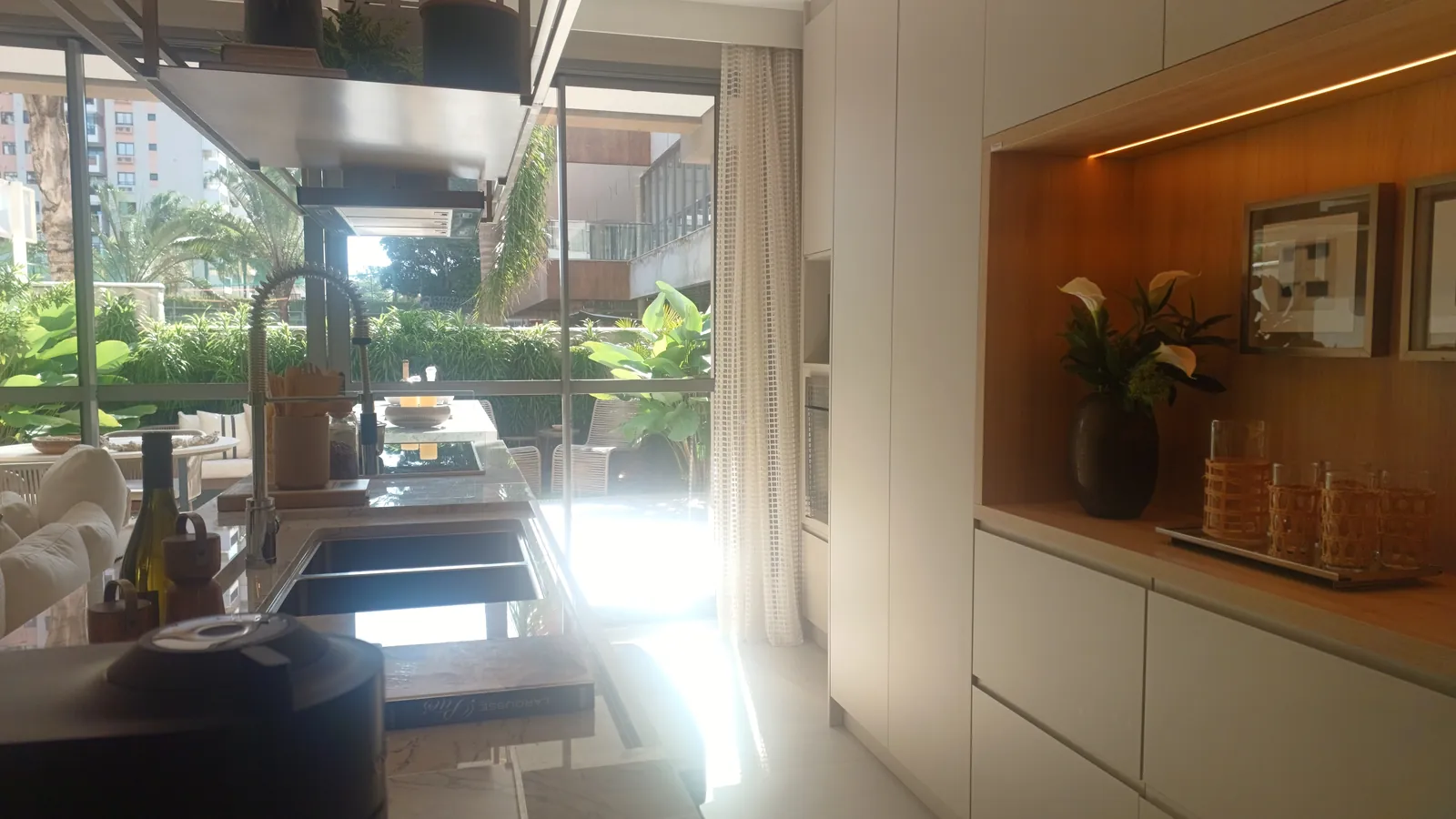 Área gourmet da casa decorada, com bancada de pedra e jardim