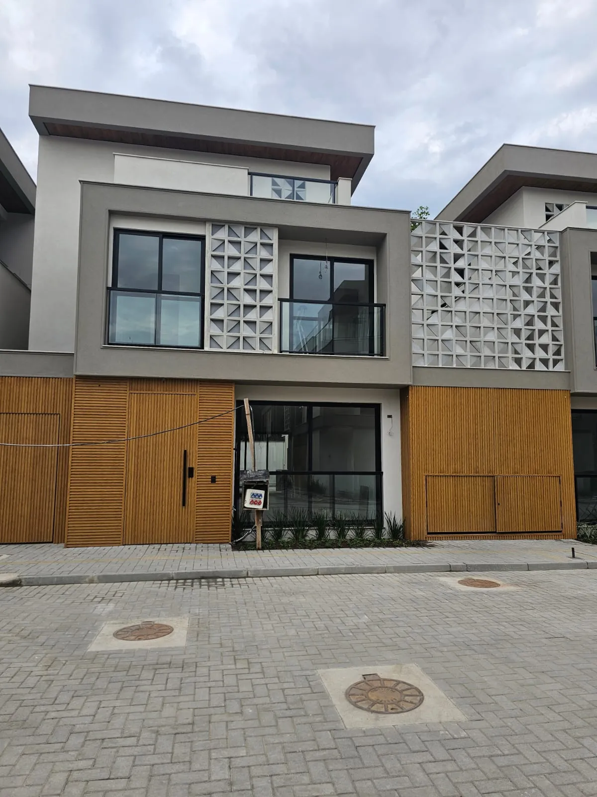 Fachada de uma casa pronta do Art Design, com portão de madeira e brise vazado
