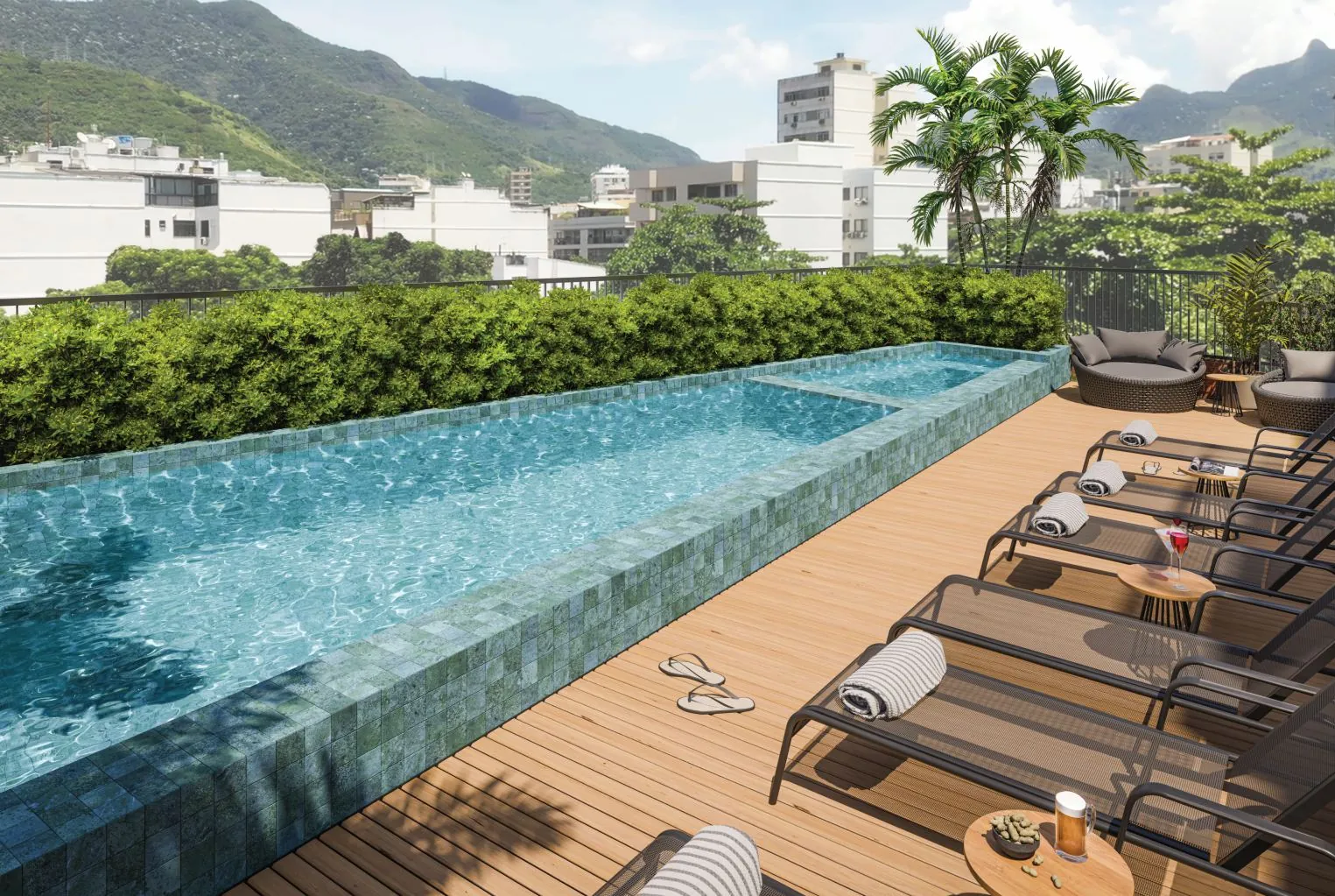 A piscina do rooftop do Cores da Tijuca, com espreguiçadeiras e vista para as montanhas