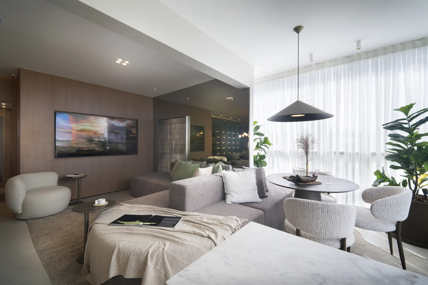 Varanda e sala de estar do decorado de 3 suítes, com poltronas claras