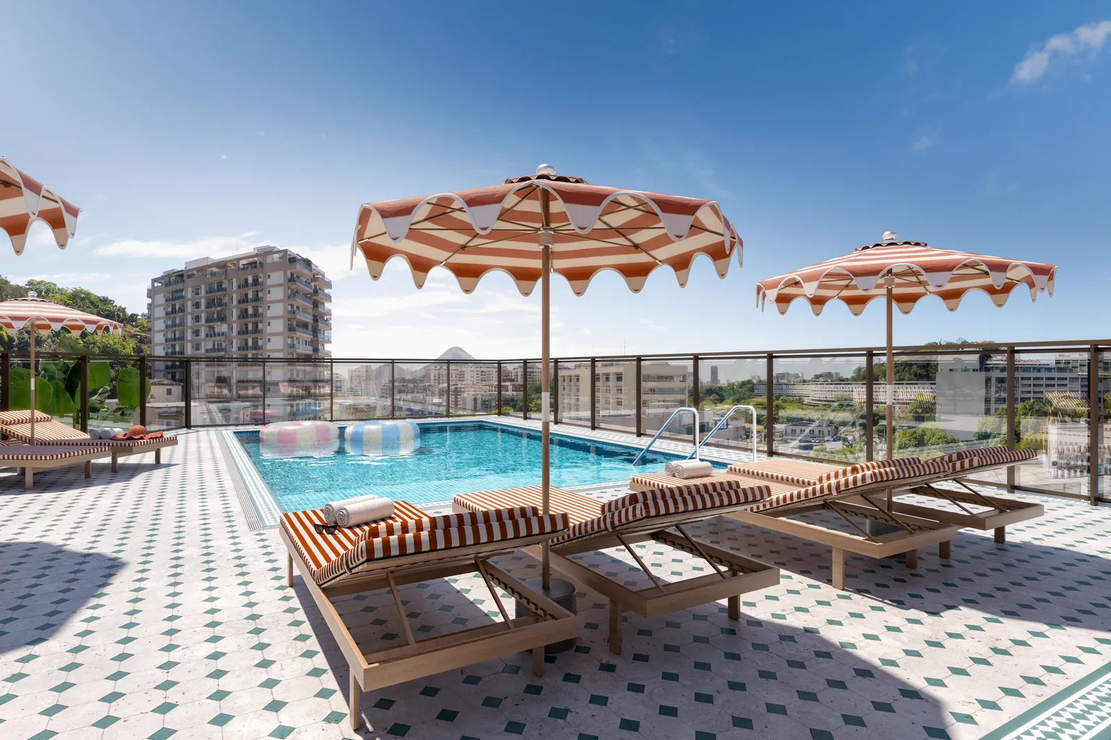 A piscina do rooftop do Gaví, com guarda-sóis listrados e espreguiçadeiras