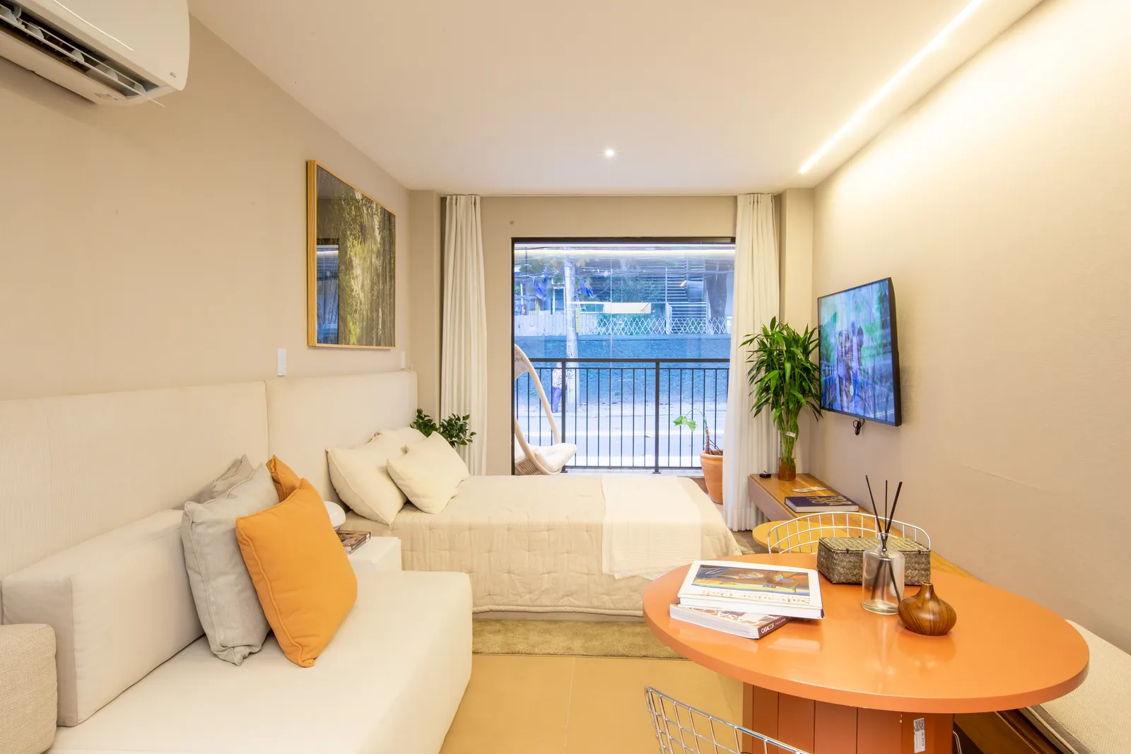 Foto do studio decorado do Gaví, com sofá-cama, mesa laranja e varanda