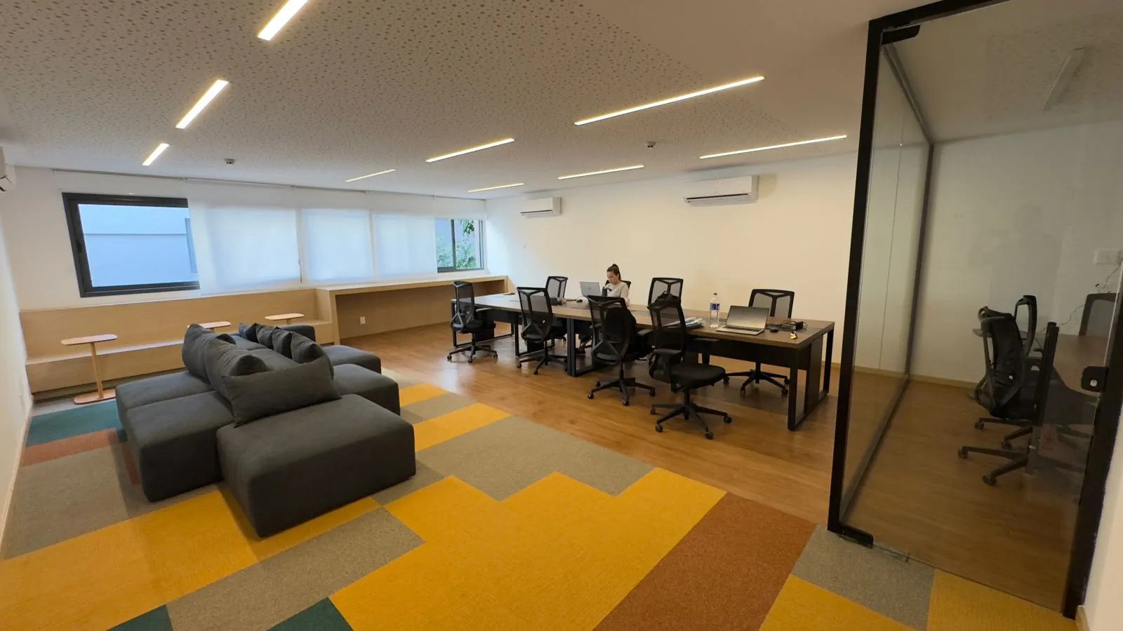 Foto real do coworking do Glória Del'Art, com mesas e sofás