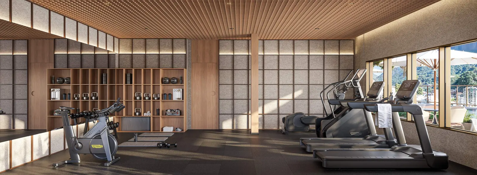 Espaço fitness com esteiras, bicicletas e grandes janelas