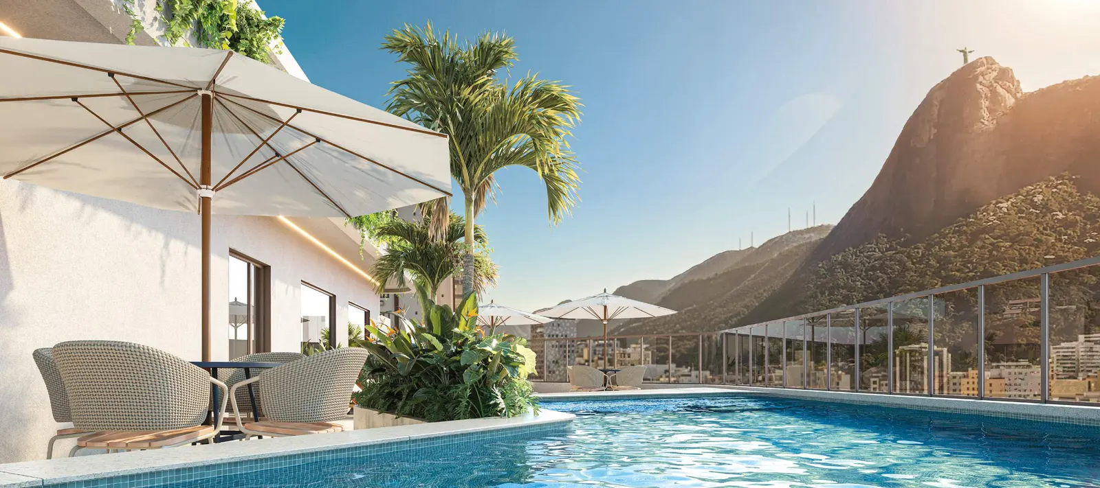 Piscina do rooftop com espreguiçadeiras, coqueiros e o Cristo Redentor ao fundo