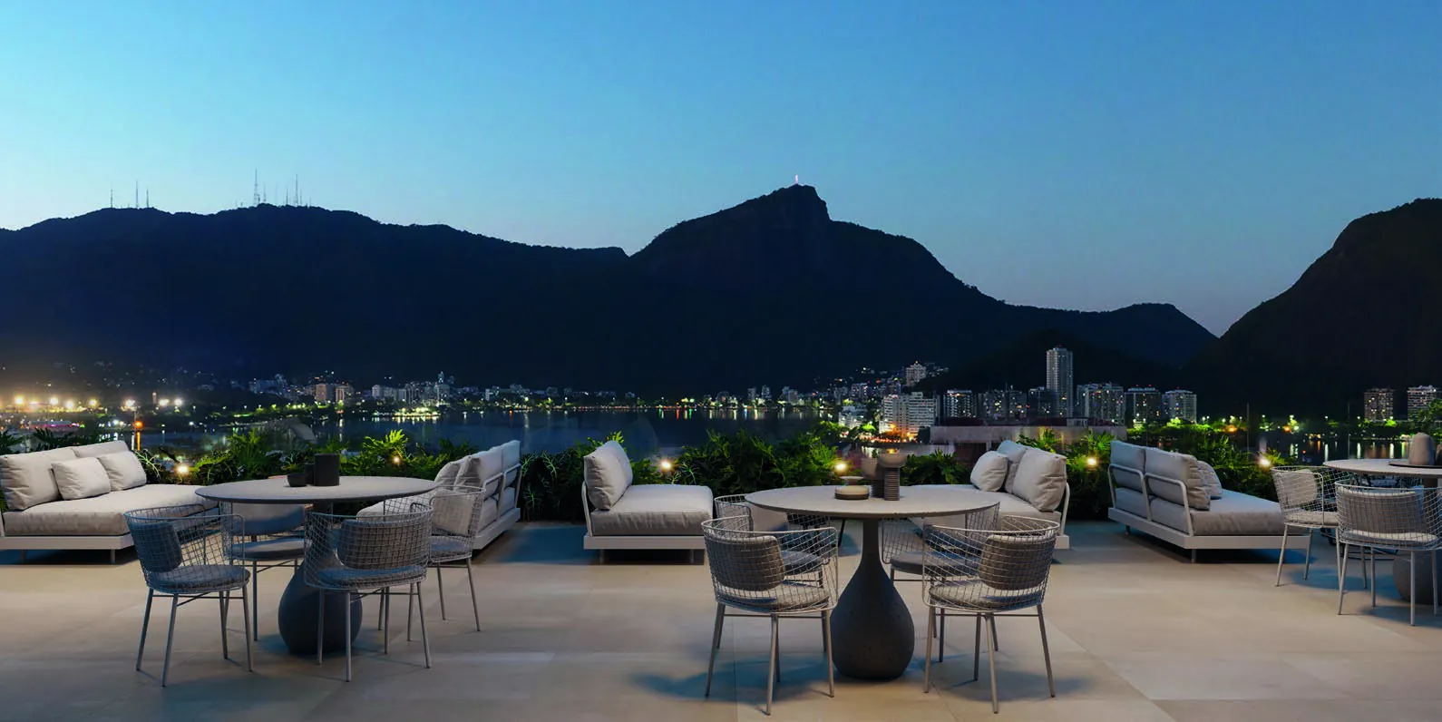 O lounge e bar do rooftop do Ipa ao entardecer, com a Lagoa e os morros