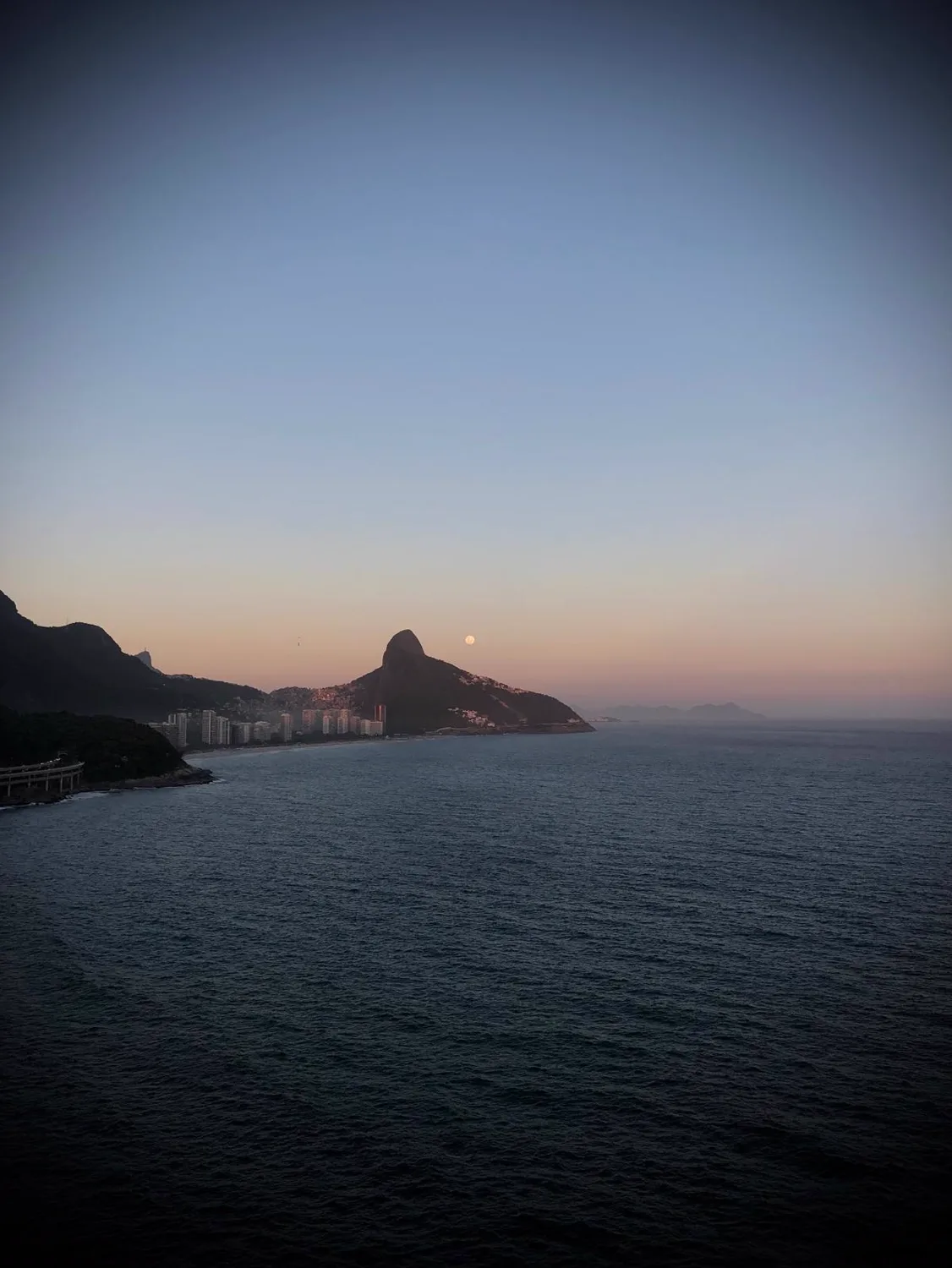 Fim de tarde visto do Joá, com o Morro Dois Irmãos e a lua sobre o mar