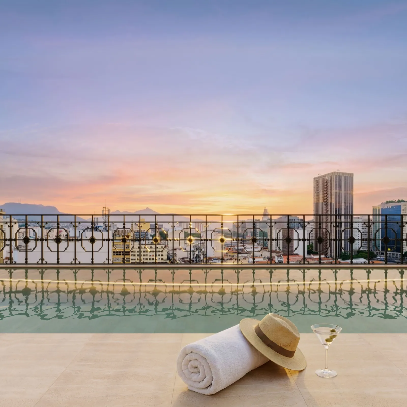 Borda da piscina do rooftop com toalha e chapéu, ao pôr do sol