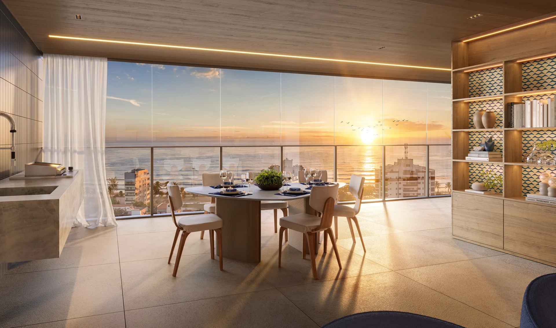 Varanda do apartamento com mesa de jantar e vista para o mar no fim da tarde
