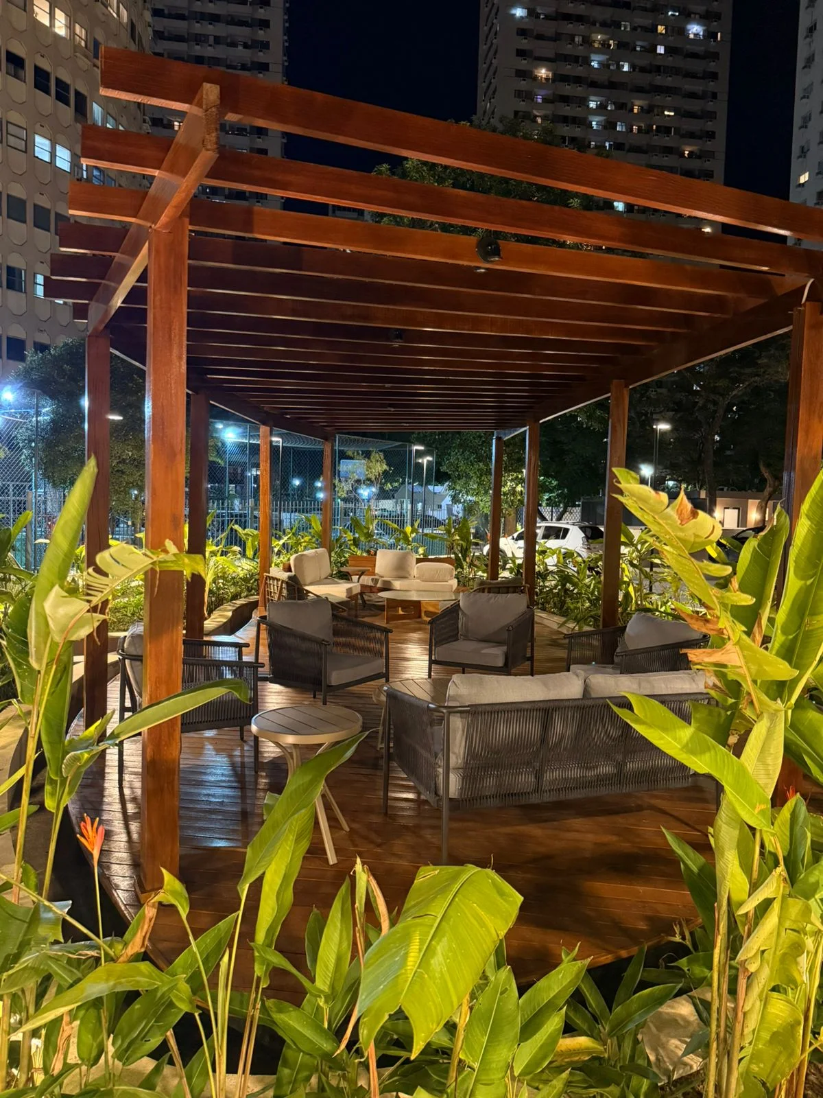 Gazebo de madeira com estar externo, iluminado à noite