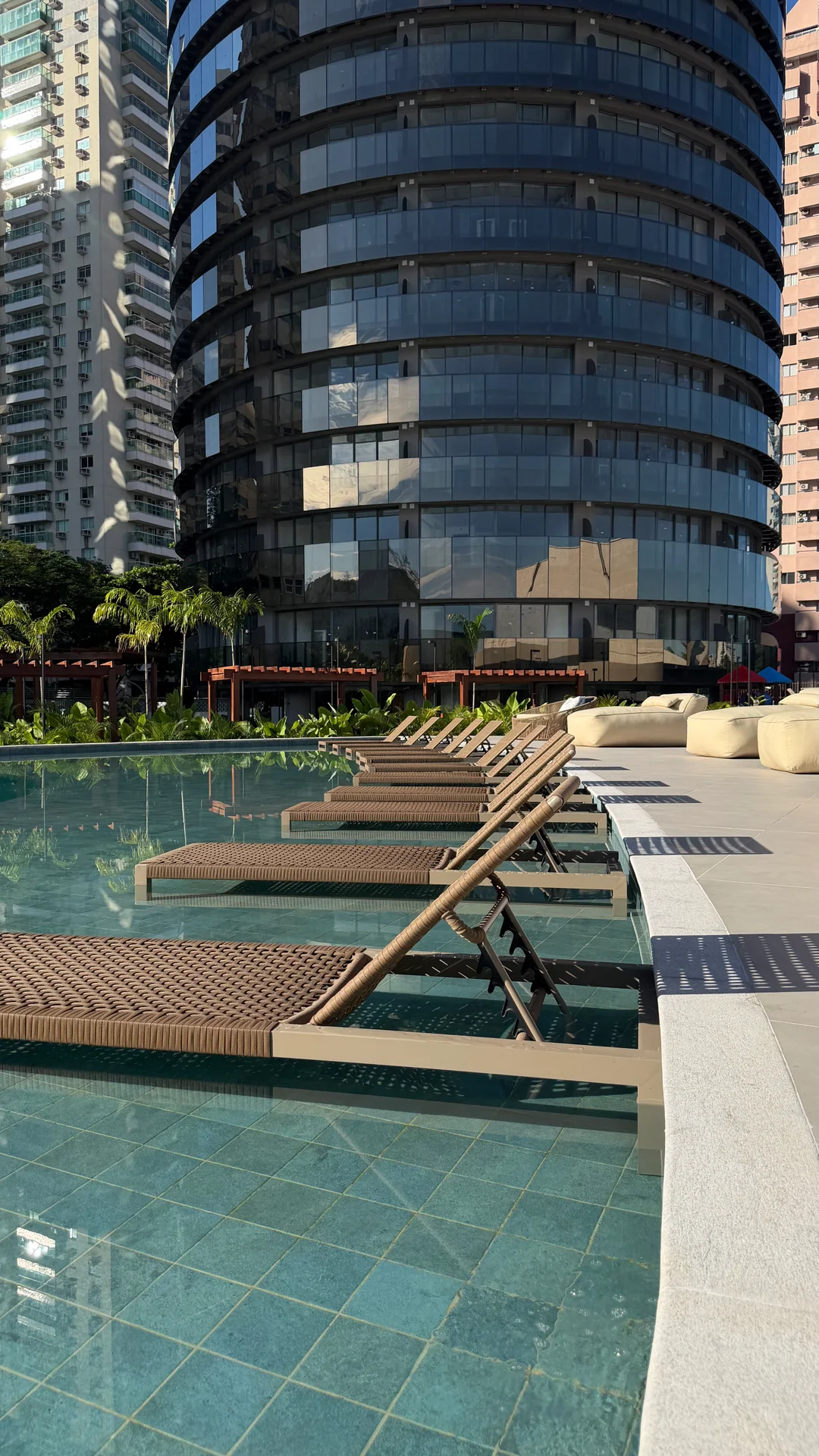 Espreguiçadeiras dentro da piscina, com a torre curva ao fundo