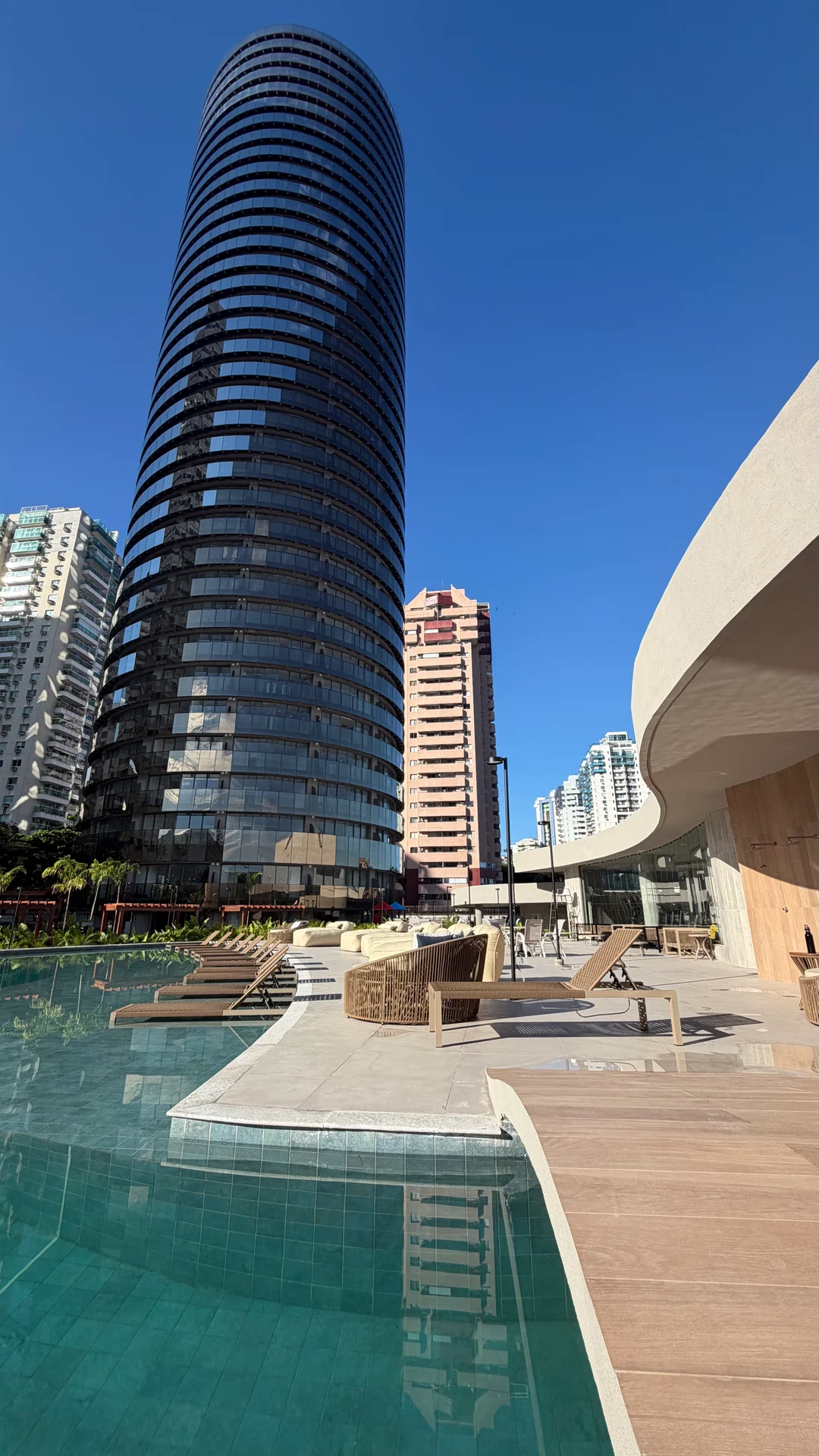 Torre em vidro reflexivo vista da piscina, em dia de céu claro
