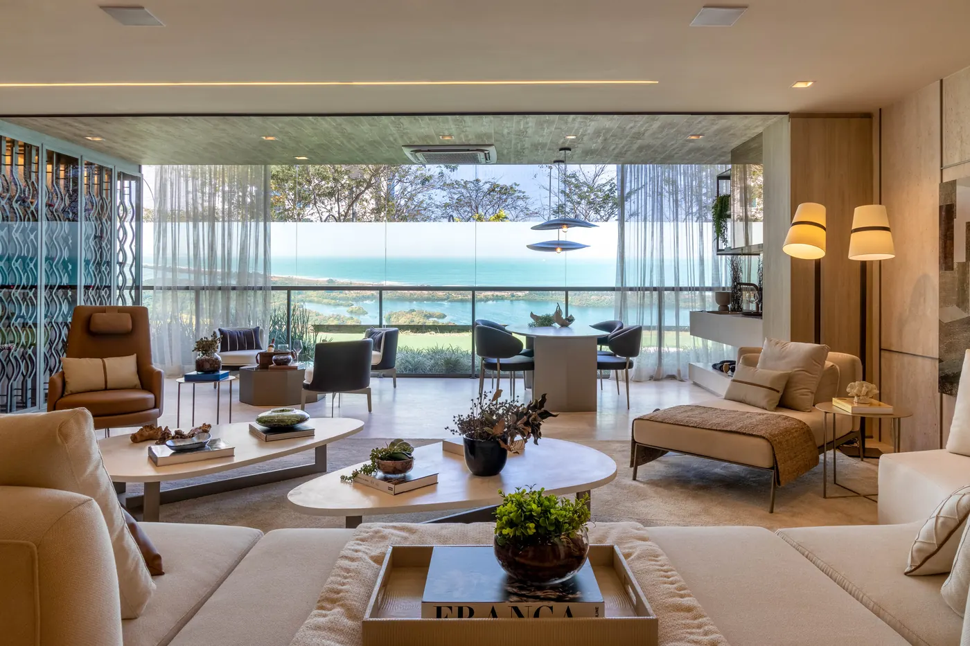 Living do apartamento decorado por Debora Aguiar, com sofás claros e vista para o mar