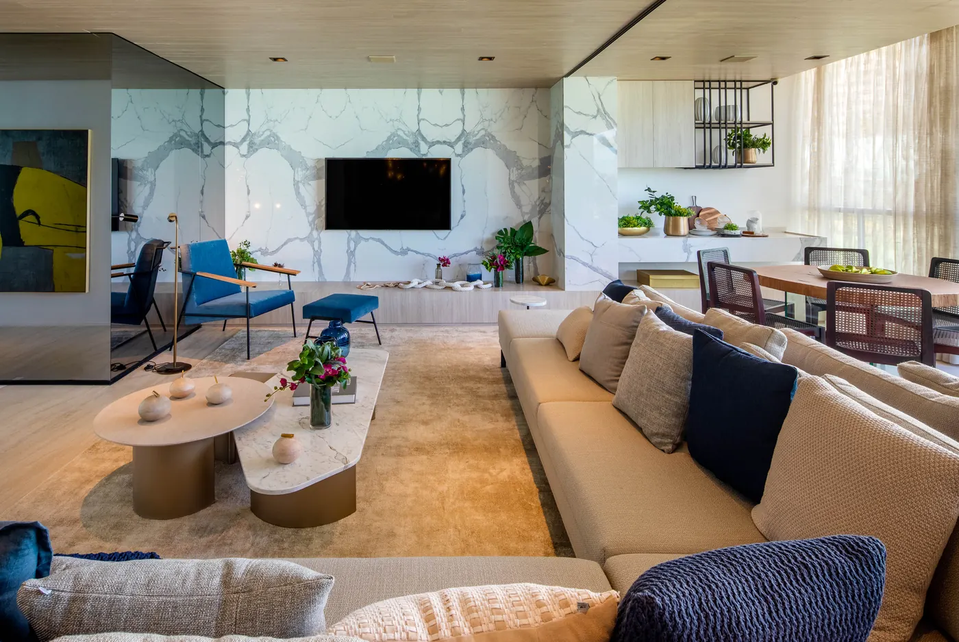 Living do apartamento decorado por Fernanda Marques, com parede de mármore e sofá azul