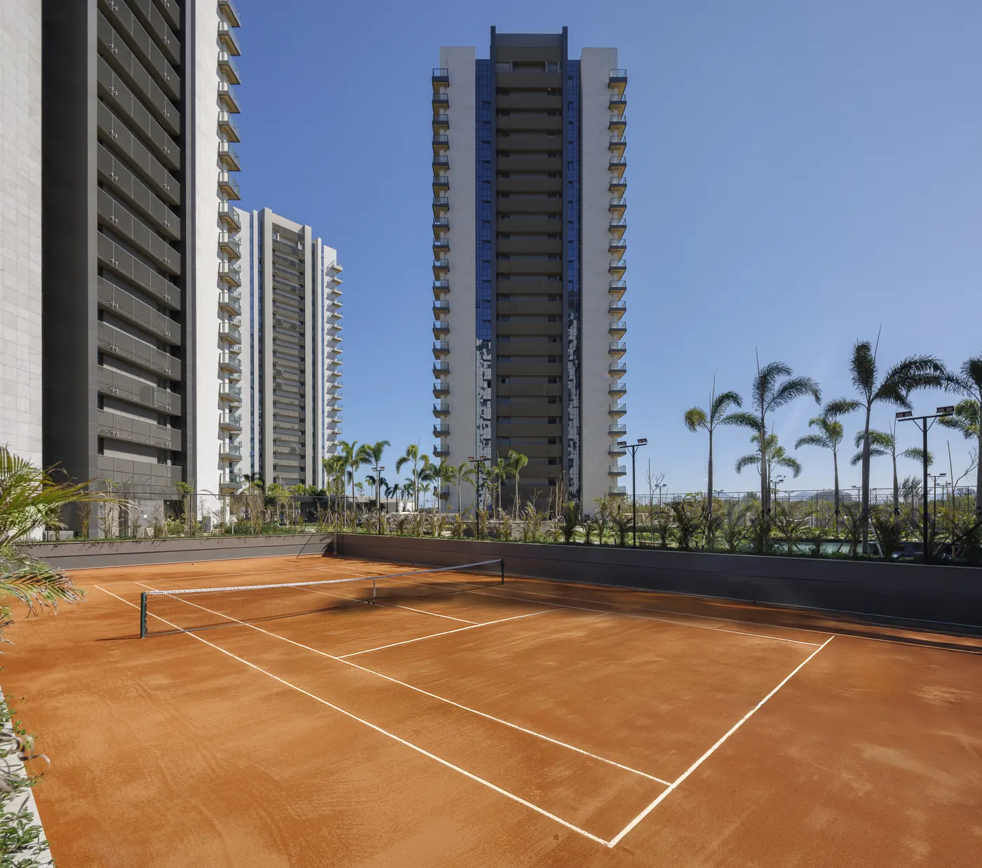 Foto real da quadra de tênis de saibro entre as torres