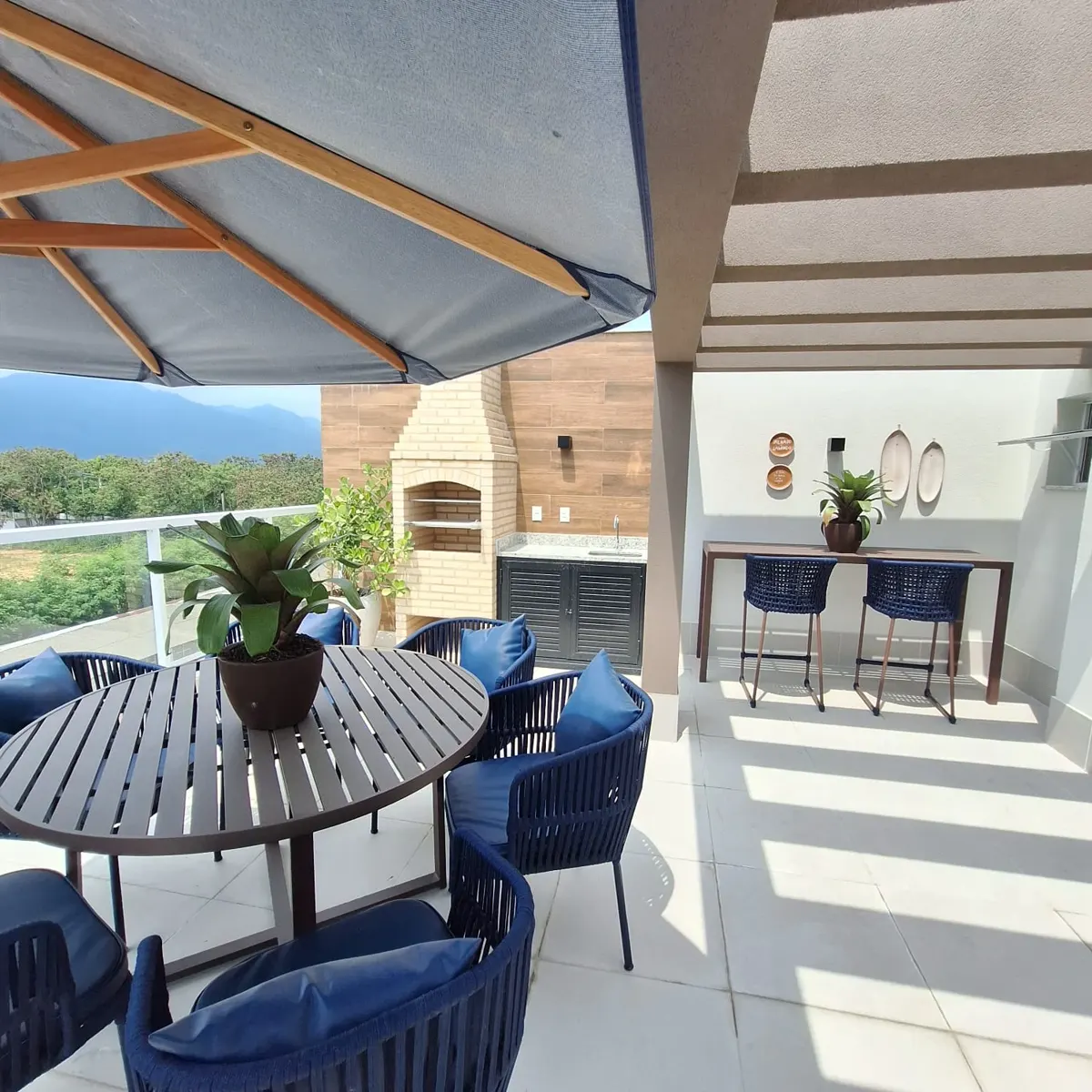 Terraço da cobertura decorada, com mesa redonda e churrasqueira