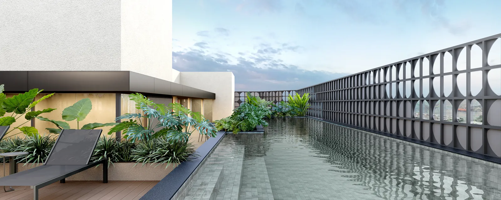 A piscina do rooftop, com deck, plantas e a fachada vazada ao lado